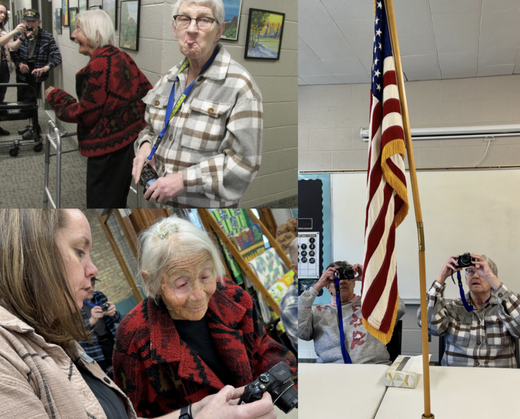 A collage of photos from a COMPAS photography workshop at Elim Oasis Adult Day Center. In one image, two older women stand in a hallway smiling and holding cameras, with framed artwork on the wall behind them. Another photo shows two women seated at a table behind an American flag, holding cameras up to their faces to take pictures. In the bottom photo, a young woman assists an elderly participant wearing a red and black sweater as they review images on a digital camera.